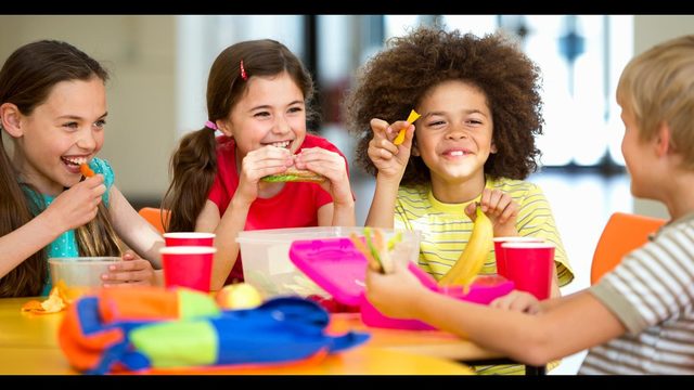 Kids at a table eating and smiling